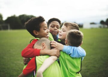 4 jongetjes die voetballen omhelzen elkaar