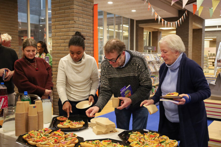 Bezoekers bibliotheek Enschede-Haaksbergen lopen samen langs een buffet vol Surinaamse lekkernij